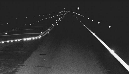 Image of lights embedded into the roadway near the coast.